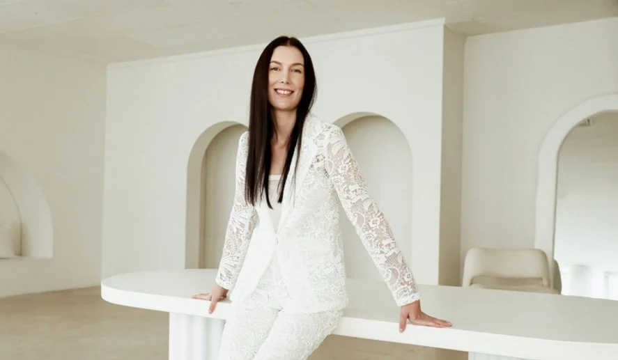 Melanie Laas, wedding content creator for EMME Weddings, in a white lace suit in a light-filled studio